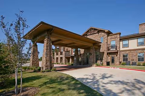 Exterior view of Isle at Watercrest Mansfield with a covered entrance and landscaped grounds.