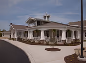 Exterior view of Rosecrest Residence: a white, curved-porch building with stone accents.