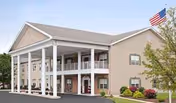 Front exterior of a beige, two-story senior living building with white columns.