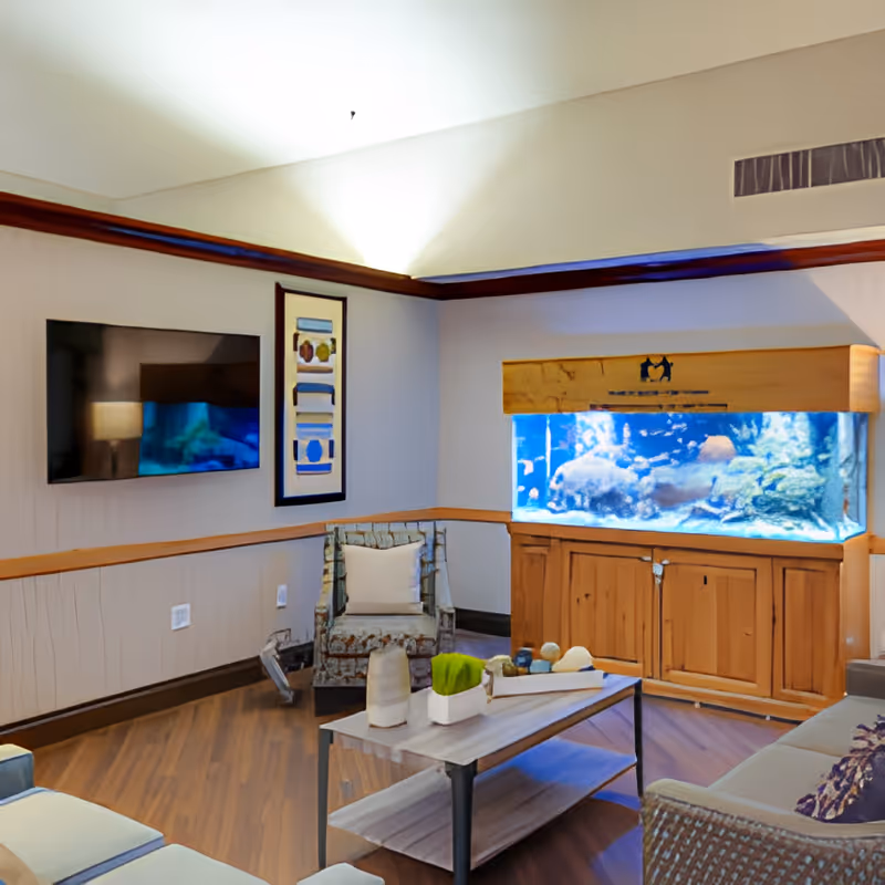 Cozy common room with an aquarium, seating, wall-mounted TV and a coffee table.