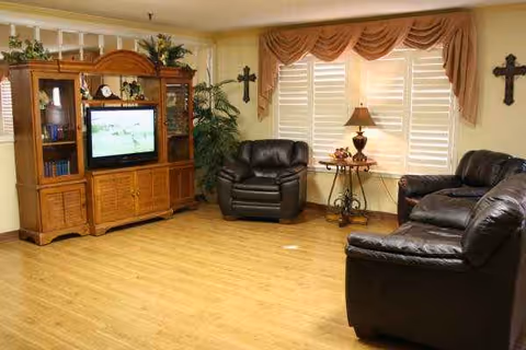 Cozy living room with leather sofas, a TV cabinet, and window blinds.