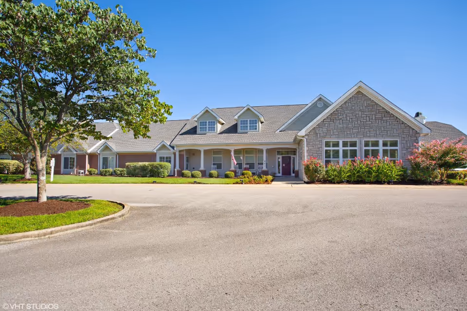 Exterior view of American House Lebanon featuring a landscaped entrance with trees and flowers, and a well-maintained facade.