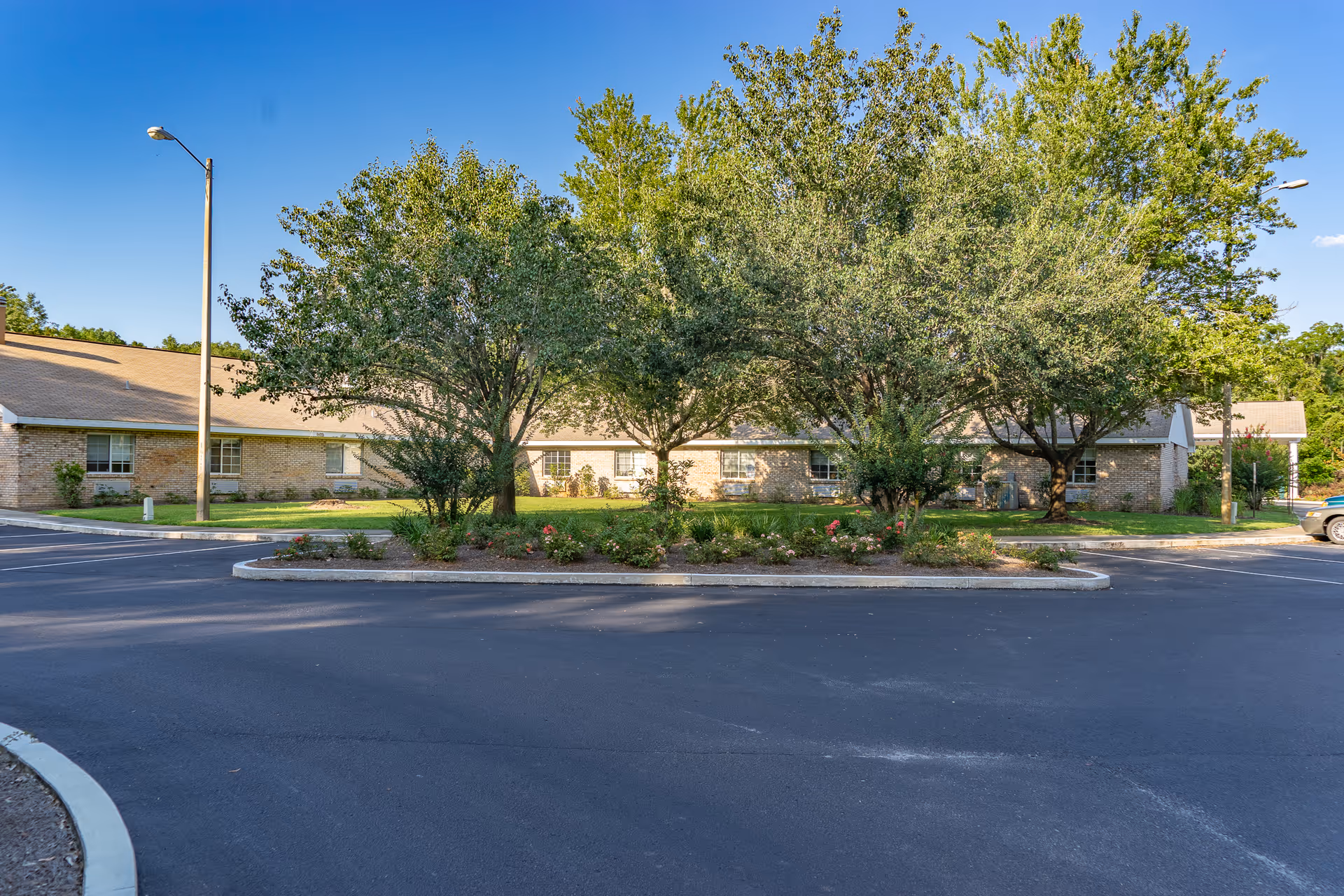 Exterior view of a single-story brick senior living facility with a circular driveway and landscaped island.