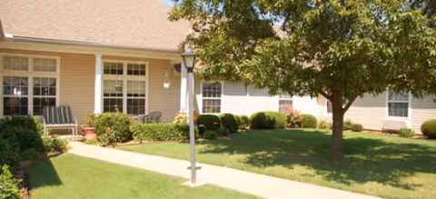 Front exterior of Brookdale Bartlesville South with lawn, walkway, and porch seating.