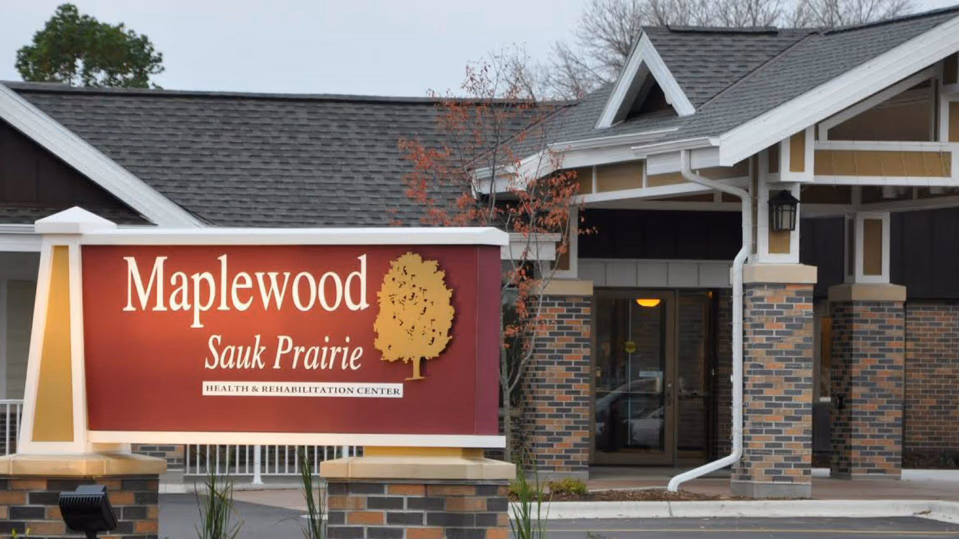 Entrance of Maplewood of Sauk Prairie health and rehabilitation center showing a large maroon sign and the building's covered entry.