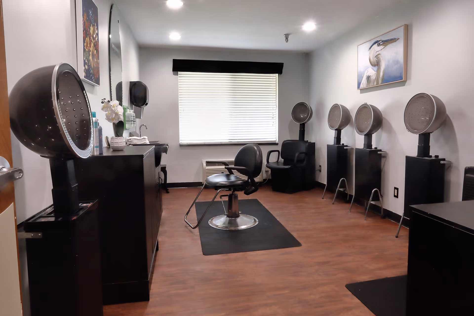 Hair salon room with salon chairs, hooded hair dryers, and a styling station.