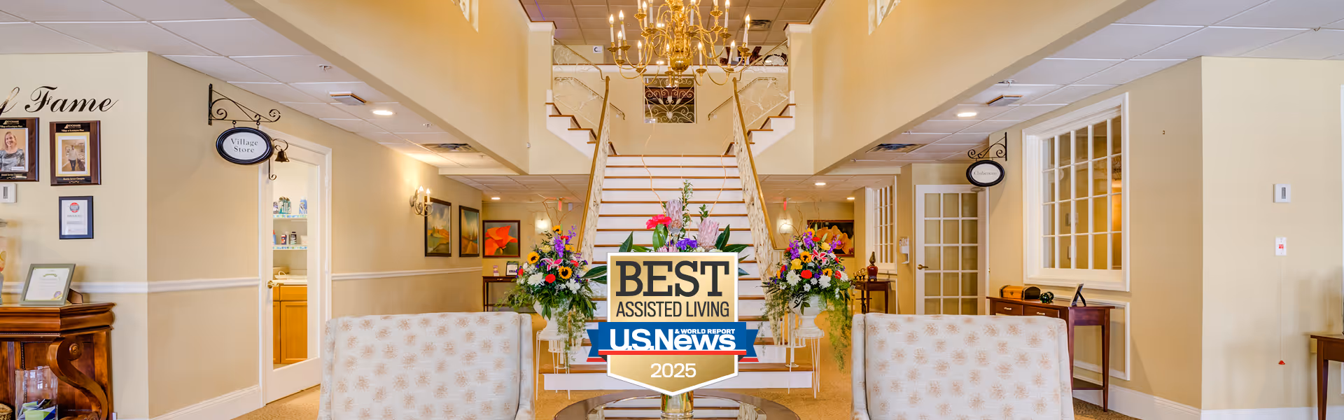 Interior view of a senior living facility with a staircase and decorative flowers.