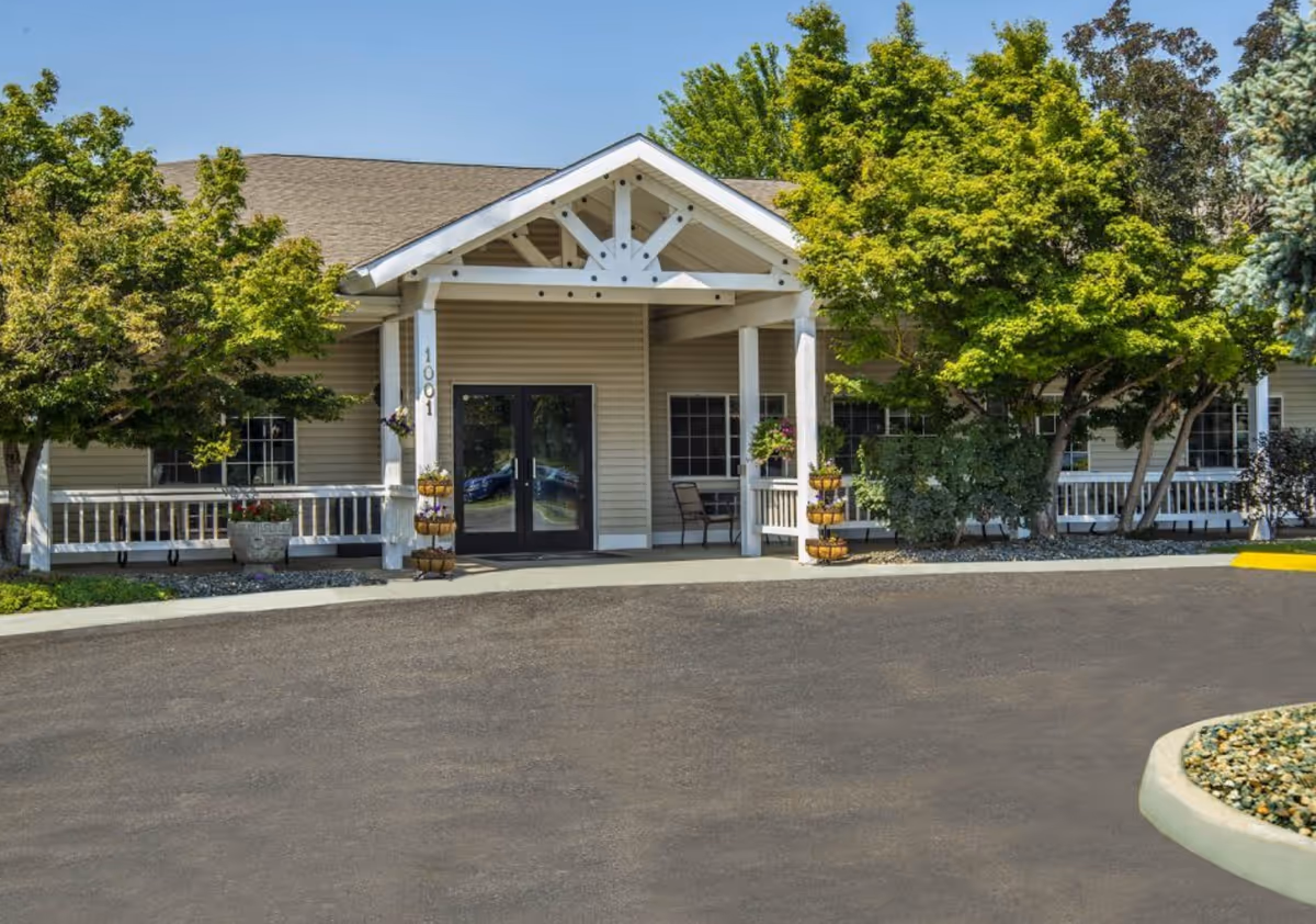 Exterior view of Apple Springs Senior Living building entrance with trees and walkway.