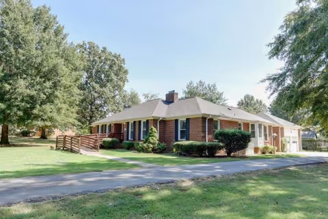 Brick single-story senior living facility with ramped entrance and green lawn.