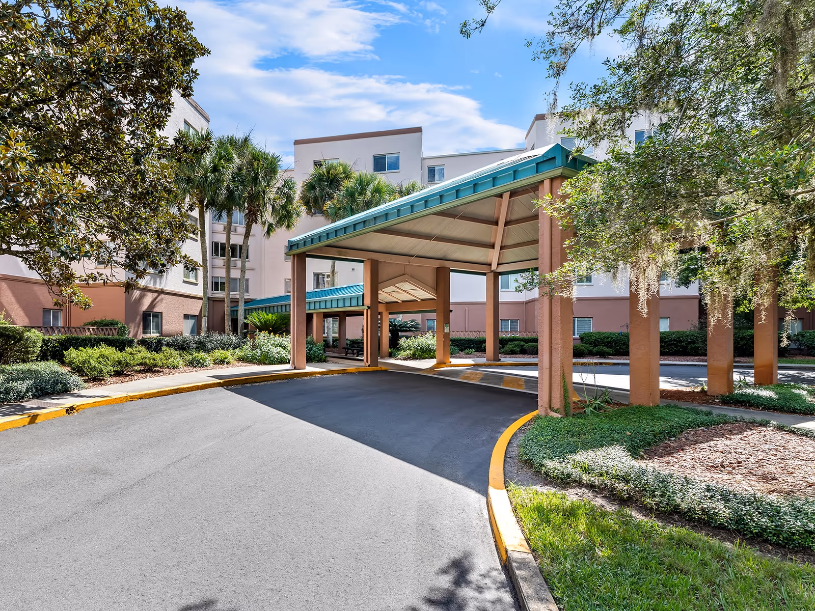 Atrium at Gainesville exterior entrance with a covered drop-off and landscaped surroundings.