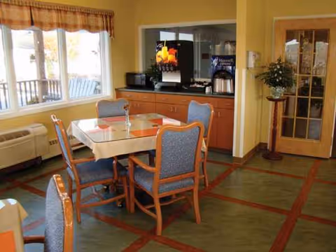 Dining room with a table, blue chairs, and a coffee station in the background.