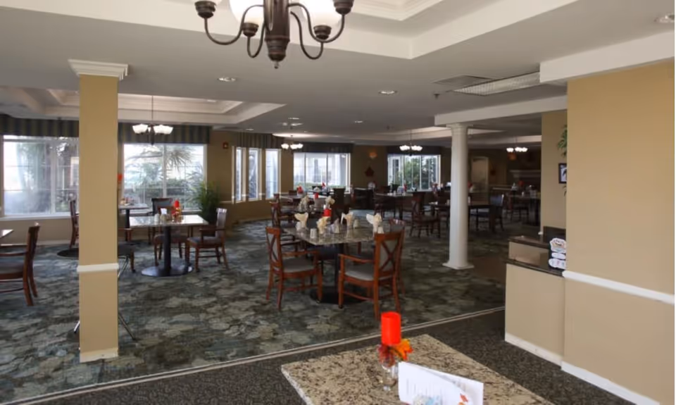 Spacious dining room with multiple set tables and chairs, chandeliers, and large windows.