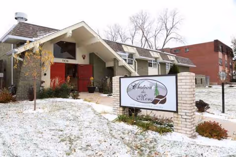 Exterior view of Chateau des Mons Care senior living facility with sign and snowy landscaping.