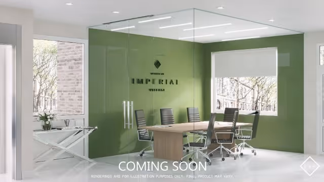 A modern conference room with glass walls and a green accent wall featuring the text 'Imperial Village'. The room contains a wooden table surrounded by six black office chairs on wheels. Large windows allow natural light to fill the space, and a small table with a vase of flowers is visible near the entrance.