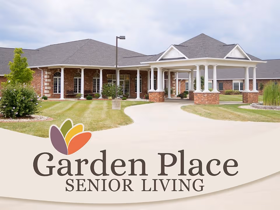 Exterior view of Garden Place Senior Living facility showing a brick building with white columns, a covered entrance, well-maintained lawn, and landscaping under a cloudy sky.