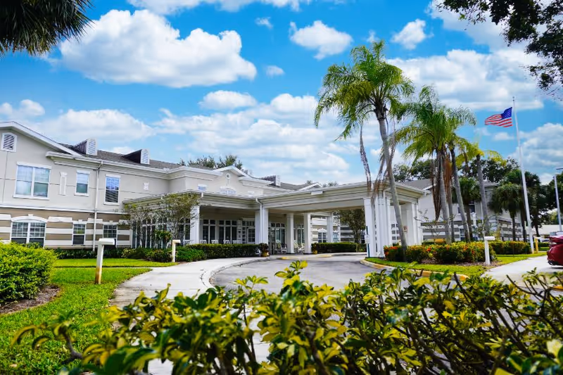 Sodalis Vero Beach senior living facility front entrance with palm trees and blue sky