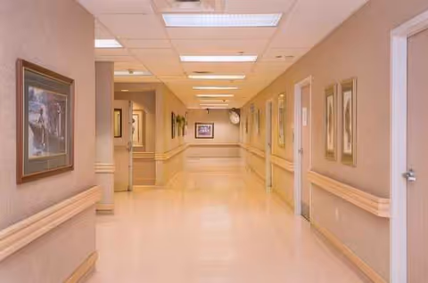 Bright hallway in a senior living facility with framed wall art along the walls.