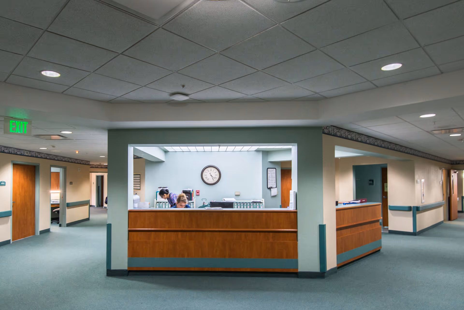 Reception area of Majestic Oaks senior living with a wooden desk, clock, and staff.