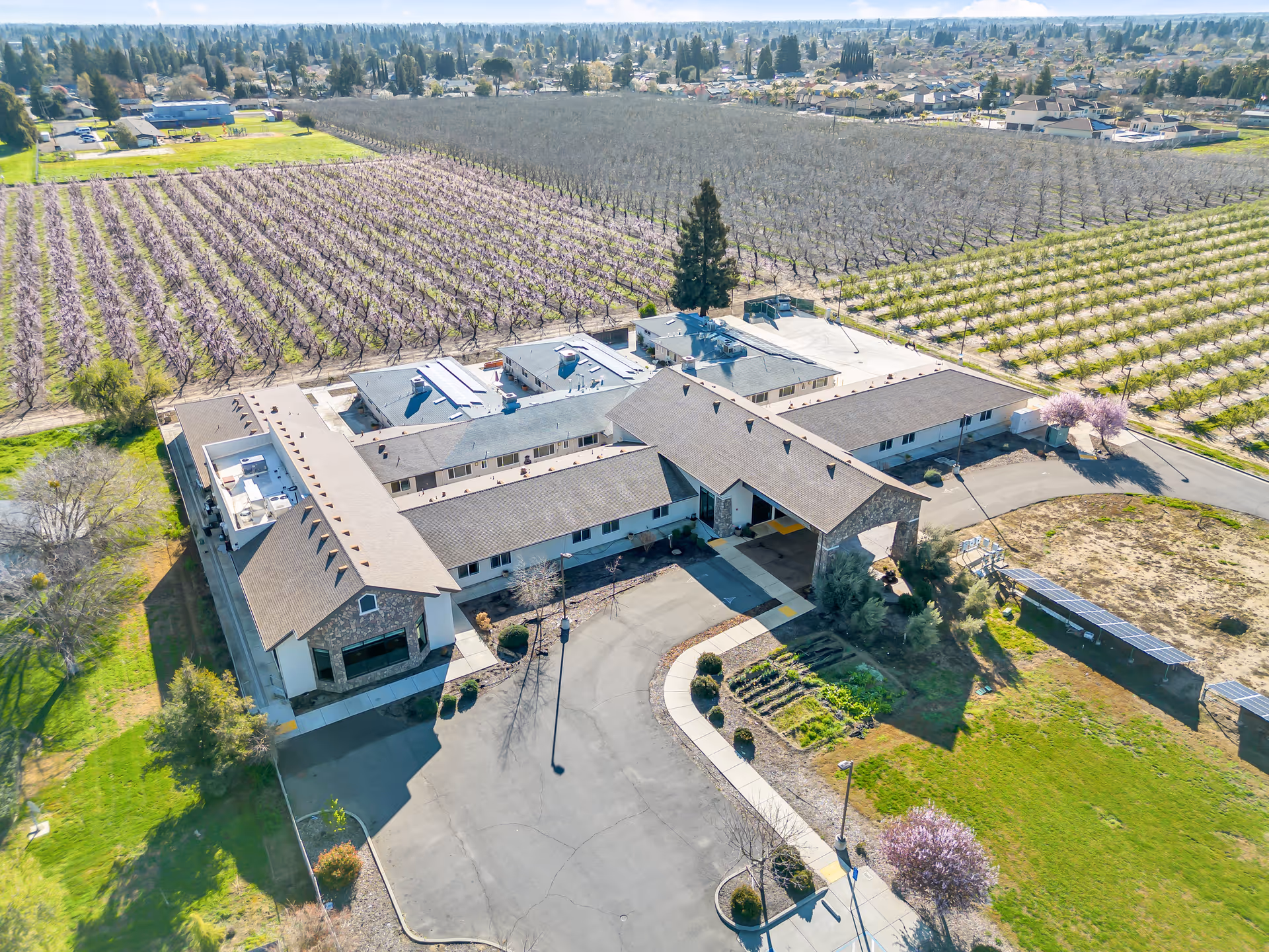 Aerial view of the Emerald Oaks Inc building and entrance surrounded by orchards and open grounds.