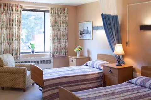 Two twin beds in a cozy hospital-style bedroom with floral curtains and nightstands.