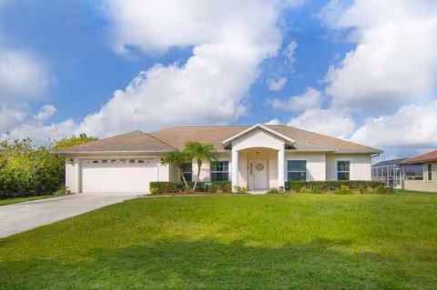Front view of a single-story beige senior living home with a manicured lawn and driveway.