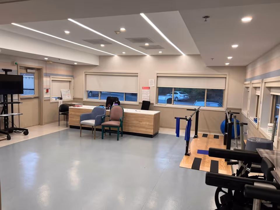 Interior rehabilitation room with a reception desk, chairs, parallel bars and other exercise equipment.