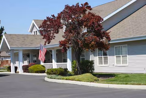 Front view of The Gables Assisted Living of Caldwell with flag and porch.