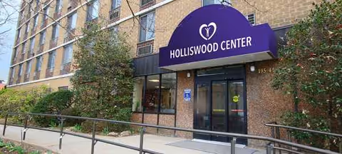Front exterior of Holliswood Center with brick facade, purple arched sign, and accessible entrance.