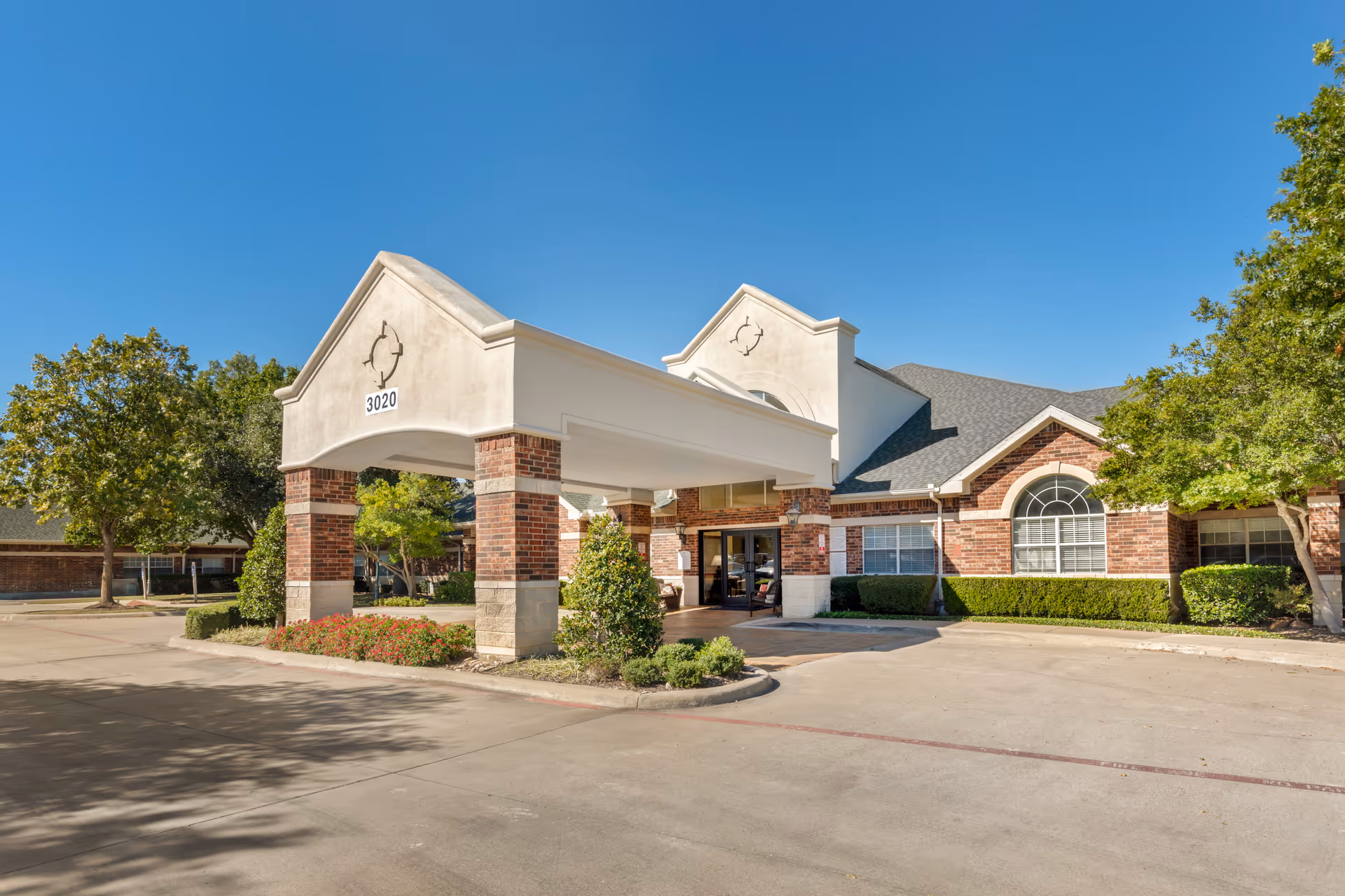 Brookdale Summer Ridge entrance with brick columns, covered drop-off, and blue sky.