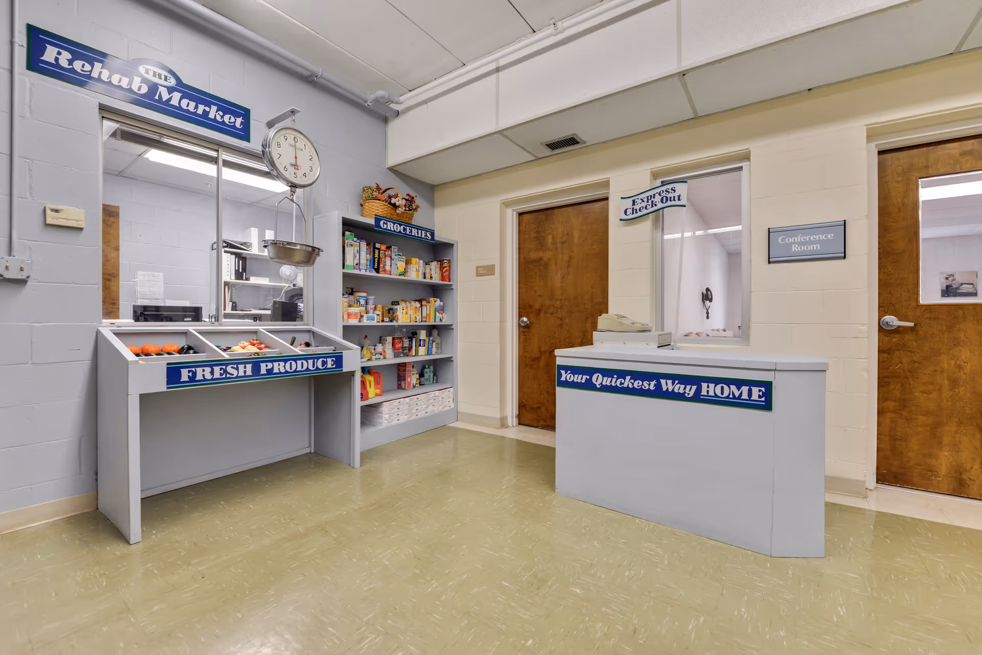 Interior view of a small market area inside a facility with a fresh produce stand, grocery shelves, and a checkout counter labeled 'Your Quickest Way HOME'. There are two wooden doors, one labeled 'Conference Room' and a window with a sign 'Express Check Out'. A clock hangs above the produce stand.
