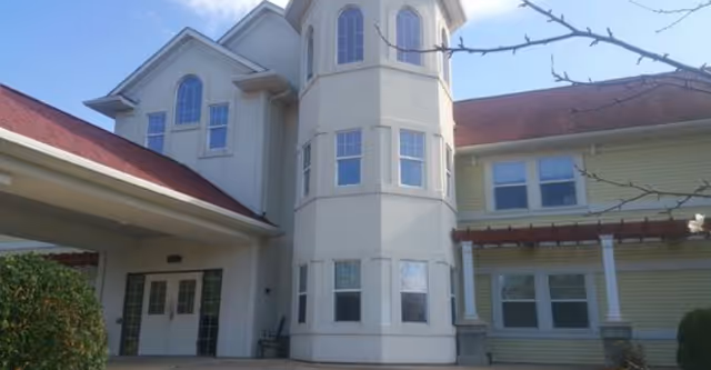 Front exterior of a multi-story building with a central turret, covered entrance, and several windows.