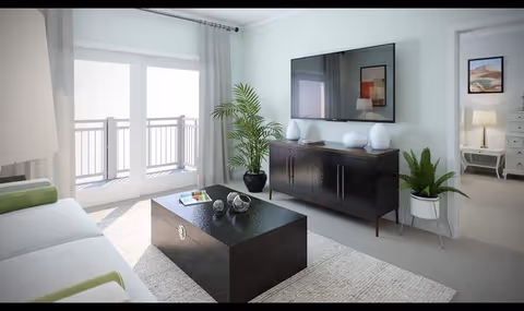 Bright modern living room with a sofa, dark coffee table, TV on a console, potted plants and sliding glass doors to a balcony.
