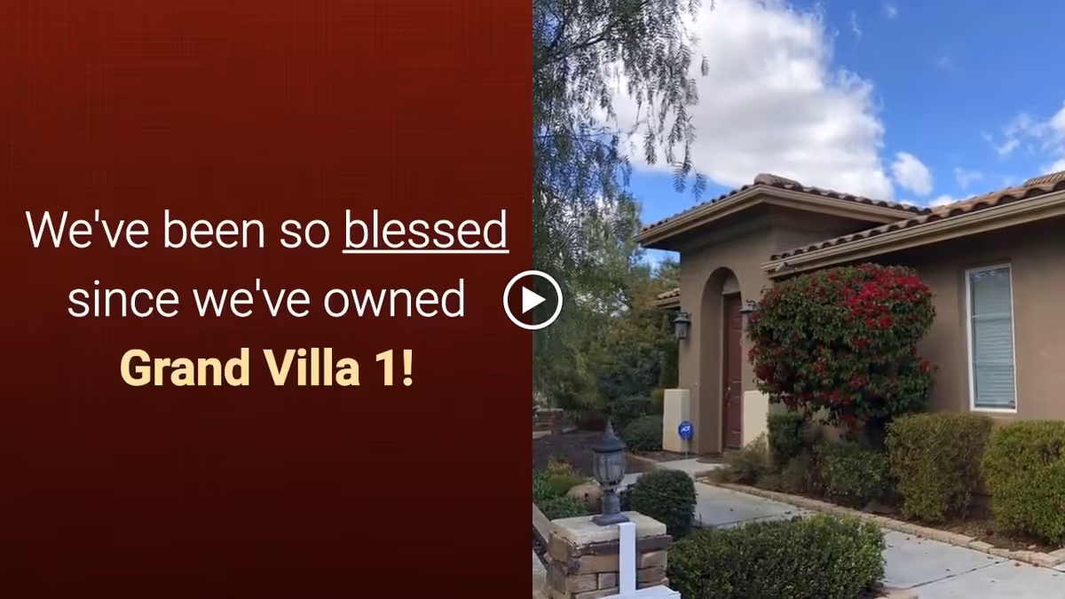 Exterior view of a single-story residential building with a tiled roof, a front door, windows, and well-maintained landscaping including bushes and a flowering shrub under a partly cloudy sky.