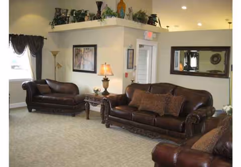 In a spacious living room, dark leather sofas, lamps, and decor create a welcoming lounge.