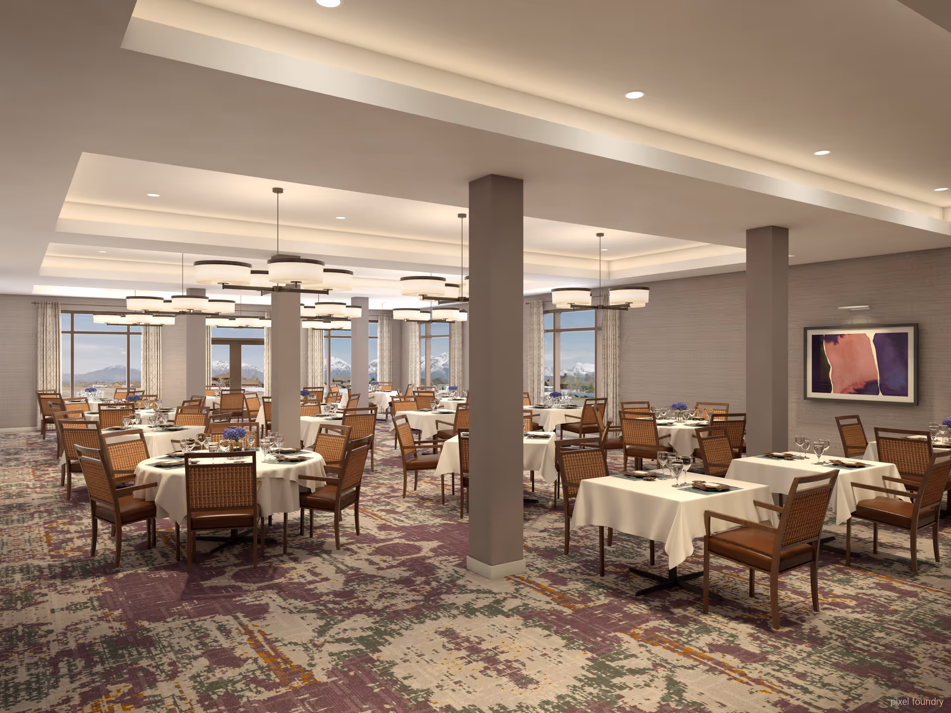 Spacious dining room with multiple round and square tables covered with white tablecloths, set with glassware and plates. The room features large windows with views of mountains, modern light fixtures hanging from the ceiling, and a patterned carpet in shades of purple, green, and beige. There is a framed abstract painting on one wall.
