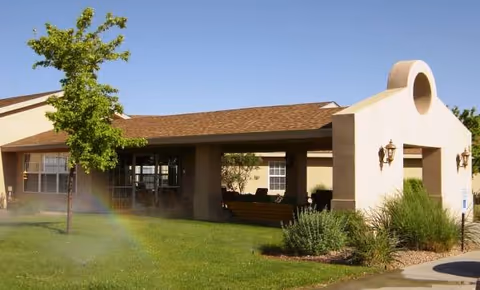 Exterior view of Cedar Ridge senior living facility with lawn, tree, and welcoming entrance.
