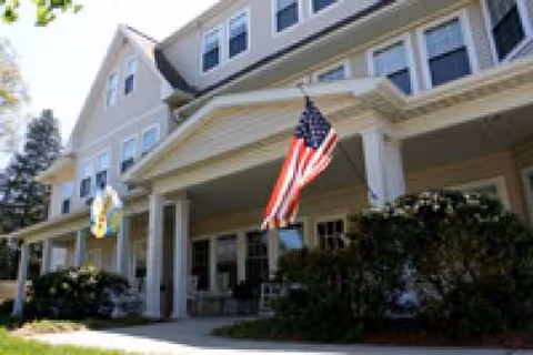 Exterior view of Twin Rivers Independent Senior Living facility with a flag at the entrance.