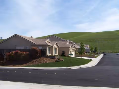 Exterior view of The Residences - Antioch, single-story beige homes along a curved street.