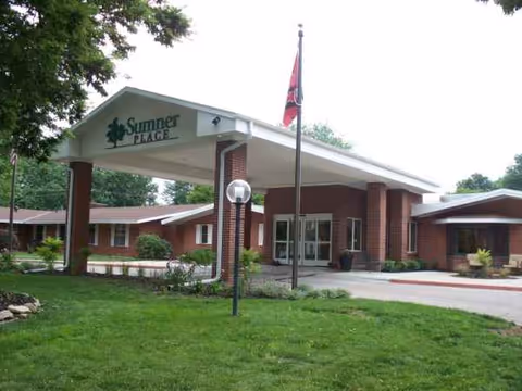 Brick facility with a covered front entrance reading Sumner Place, flagpole, and landscaped lawn.