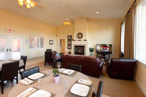 Interior common area with round dining table, couches, fireplace, and TV.