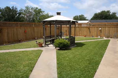 Outdoor courtyard with gazebo, lawn, and surrounding fence at Groesbeck LTC Nursing-Rehab