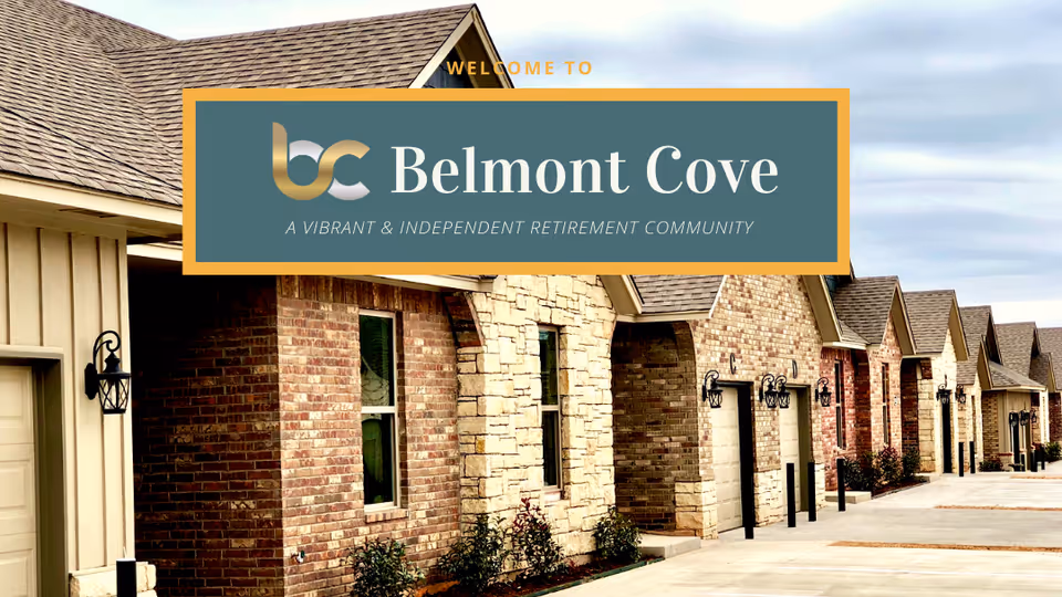 Row of brick-and-stone single-story senior living units with garages and a large 'Belmont Cove' sign overlaid at the top.