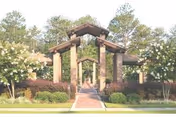 Brick covered entrance pavilion with columns, a paved walkway and landscaped trees and shrubs.