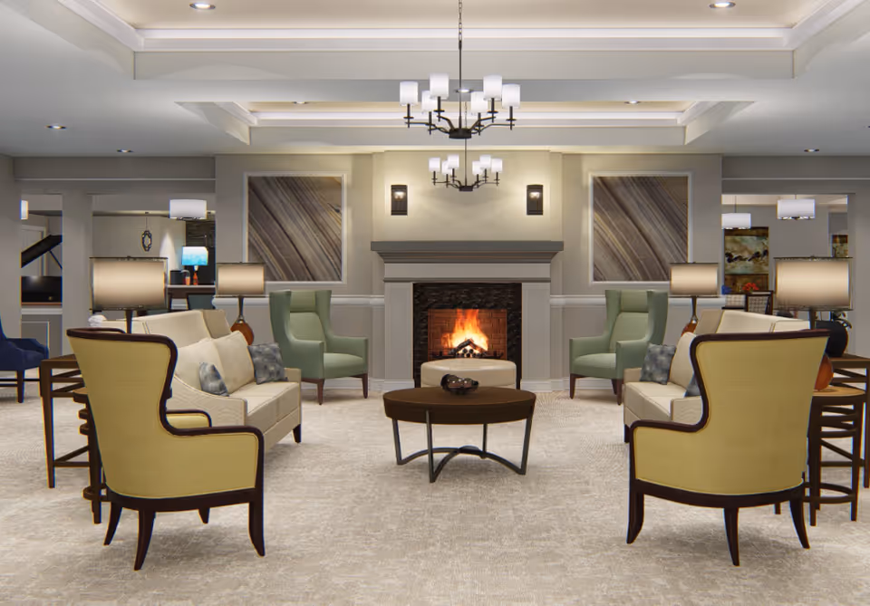 Bright, well-appointed communal living room with armchairs and sofas arranged around a lit fireplace and central coffee table.