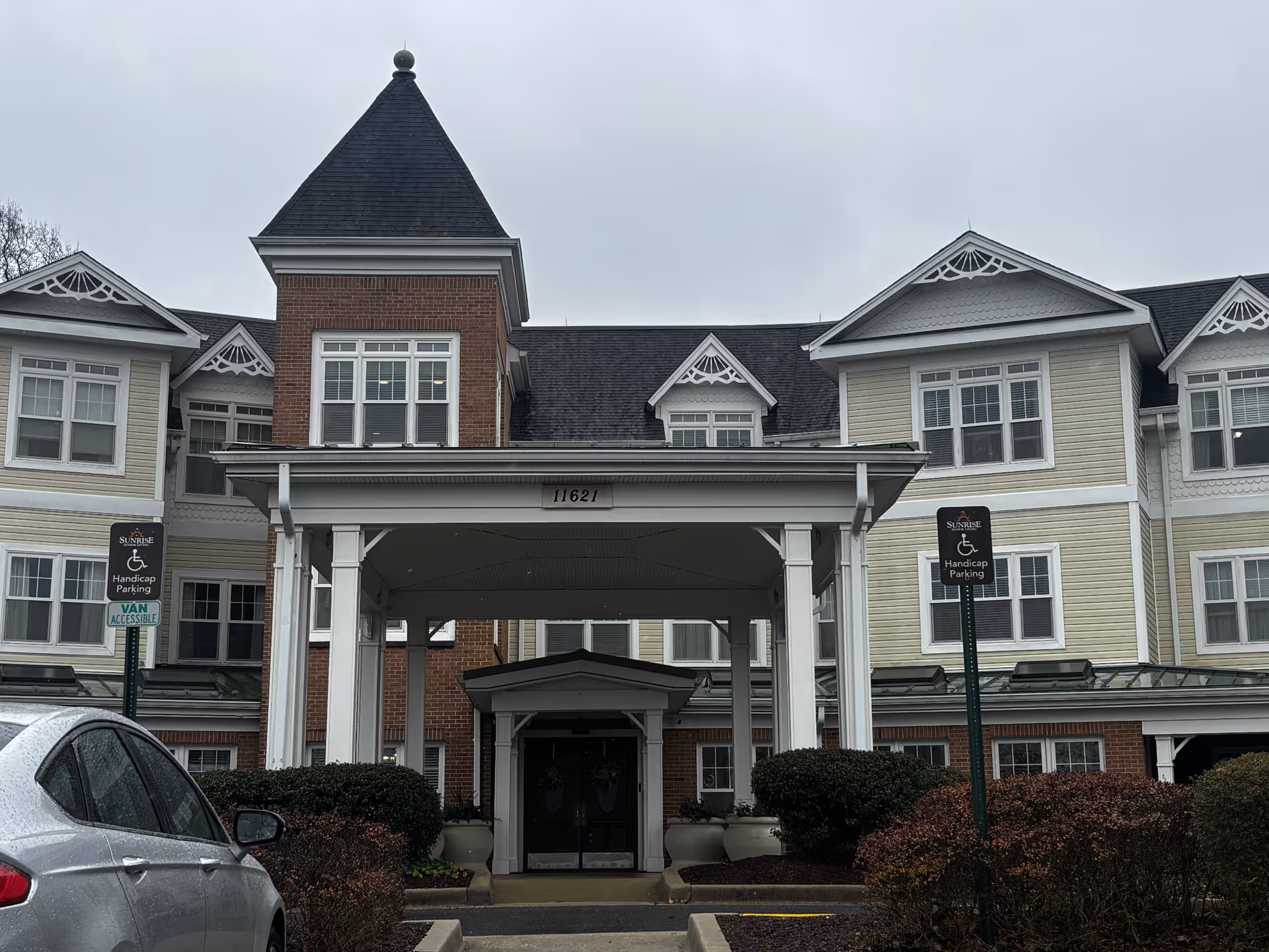 Front entrance of the Sunrise of Silver Spring building with a covered porte-cochere, address number above it, and handicap parking signs.