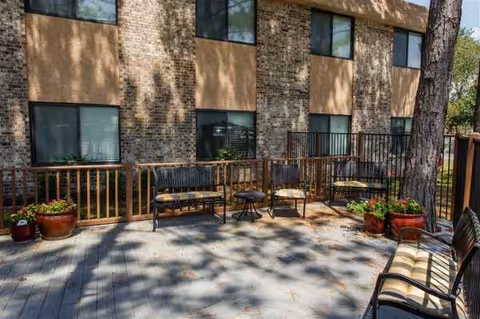 Outdoor patio at Ashford Gardens with seating, potted plants, and a brick building backdrop.