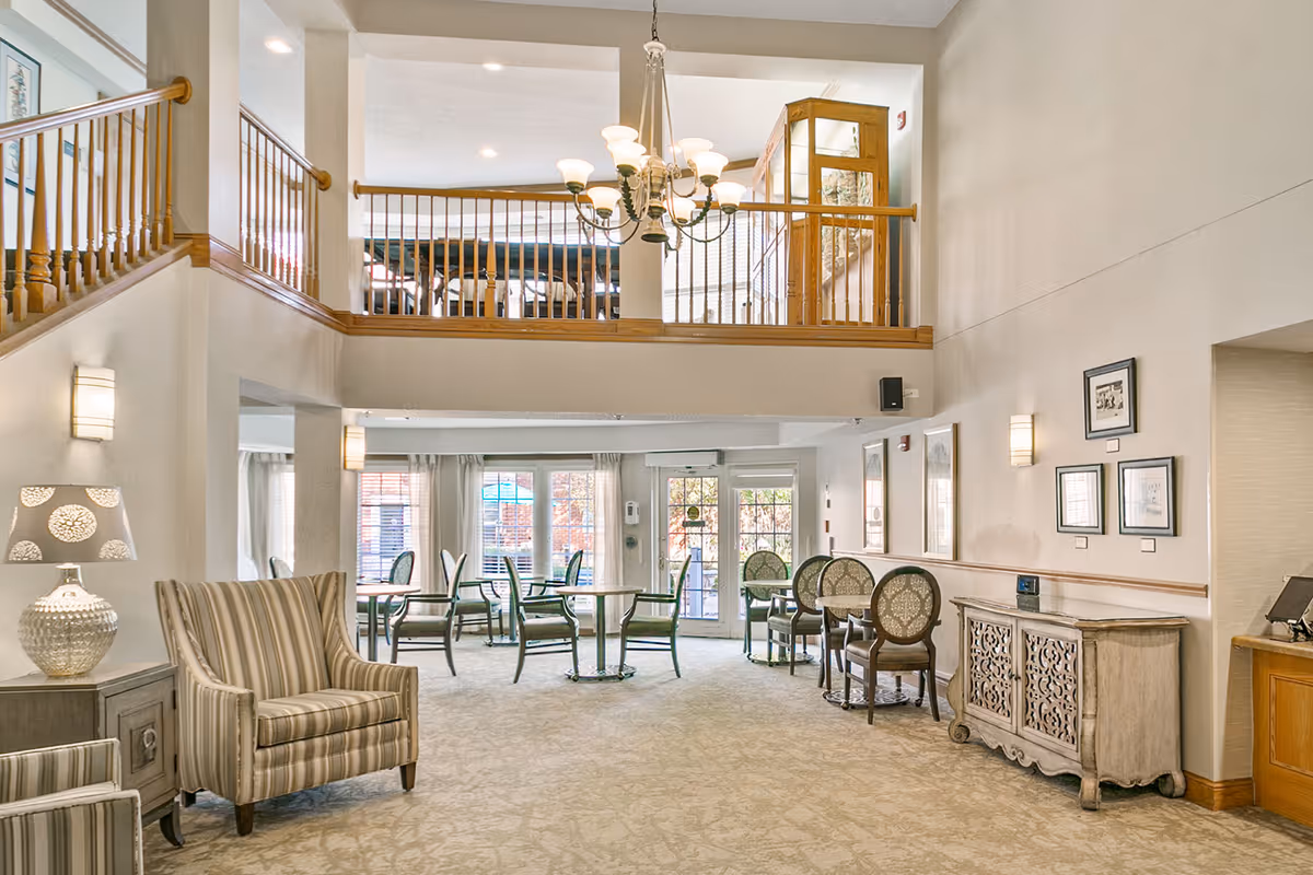 Bright two-story common area with seating, dining tables, and a chandelier.