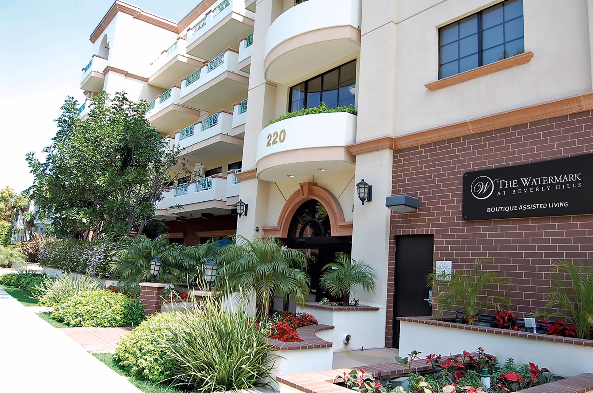 The entrance of The Watermark at Beverly Hills, a senior living facility, surrounded by lush landscaping.