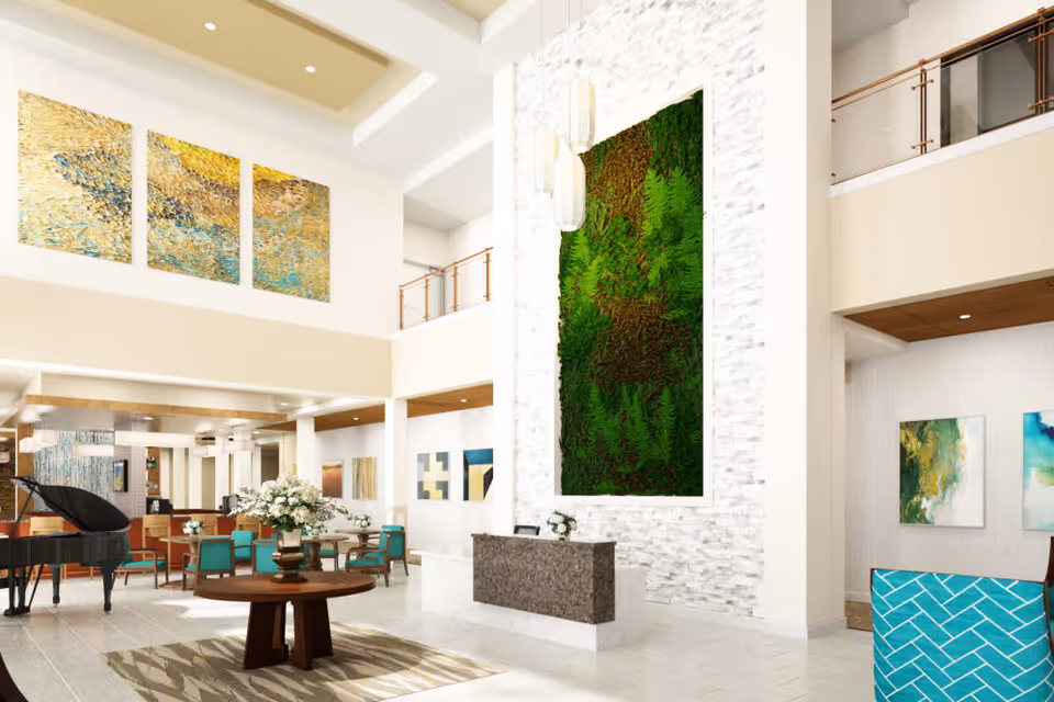 Bright modern two-story lobby with seating, a reception desk, a grand piano, and a large vertical green plant wall.