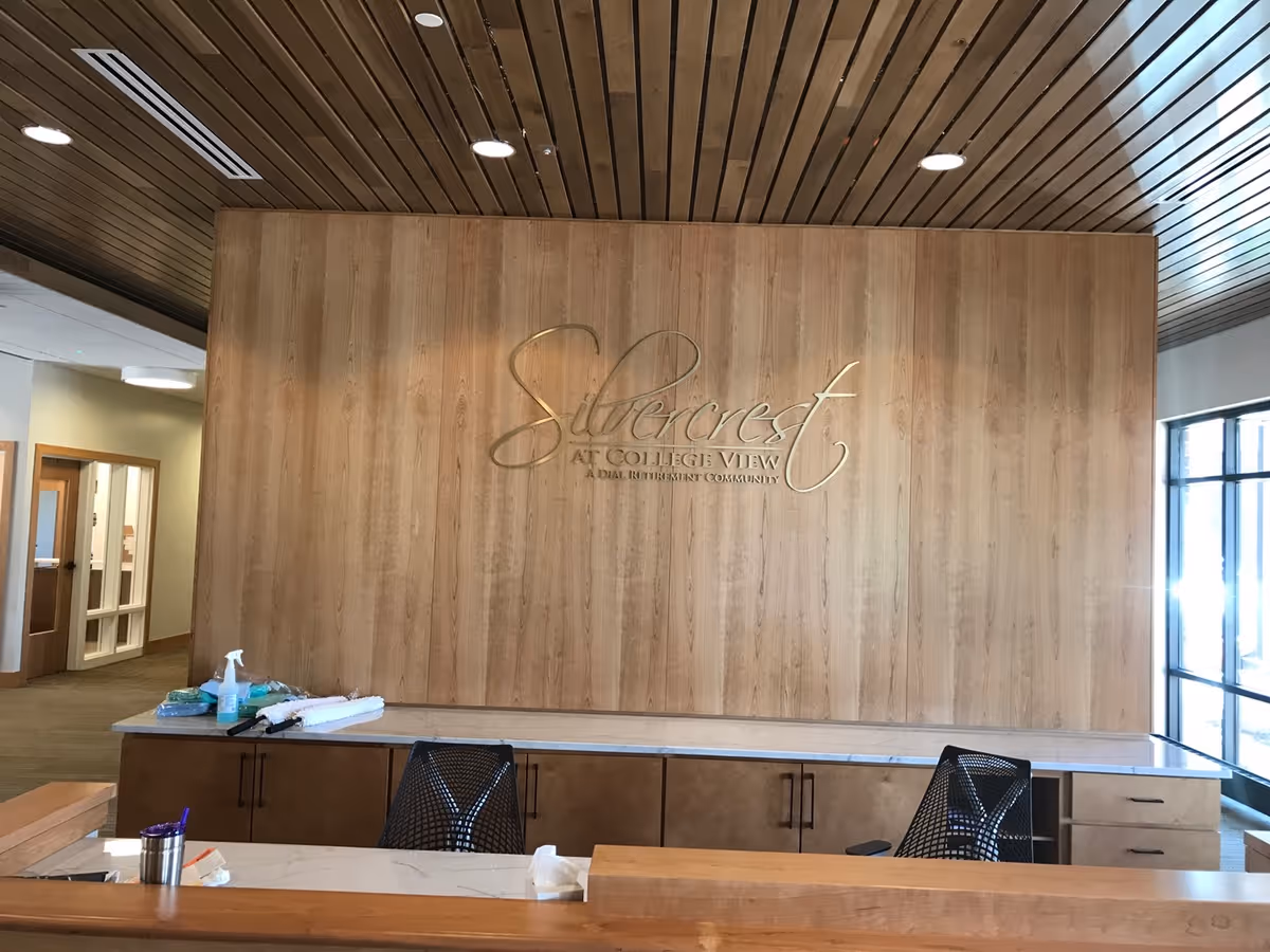 Reception desk and wood-paneled wall with the 'Silvercrest at College View' logo in a senior living facility lobby.